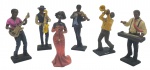 Grupo escultórico com a representação de uma banda com cinco músicos e uma cantora; em resina policromada. Medidas: 13 x 7 cm. Cantora e saxofonista com sinais de restauro; violinista sem o arco do violino.