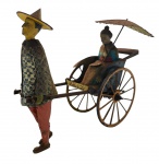 LEHMANN - MASUYAMA - Antigo brinquedo fabricado na Alemanha por volta de 1927-1938, feito em lata litografada movido a corda, sendo um homem puxando um riquixá com um passageiro sentado. Medida: 18cm aproximadamente. Observação: Pontos de oxidação na peça, desgastes e marcas, avaria no guarda-sol, defeito na corda.
