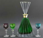 01 licoreira de estilo Art Déco, em cristal translúcido e na cor verde e com tampa e corpo moldados em forma de leque e ondulações; e 03 taças de licor de diferentes cores da manufatura BEYER BLEIKRISTALL, GERMANY, em cristal double lapidado com elementos florais, vegetalistas e ovais, e pé alto com haste multifacetada. Bocal da licoreira em metal espessurado à prata. Medidas: 32 x 17 cm; 12 x 15 cm. Base da licoreira com três ínfimos bicados; base da tampa da licoreira com ínfimo bicado.
