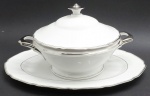 CT TIELSCH ALTWASSER, GERMANY - Parte de serviço de jantar com 01 terrina circular e 01 travessa oval, em porcelana alemã; pega da tampa e alças da terrina, faixas e filetes adornados na cor prata. Marca da manufatura na base. Numerados. Medidas: 29 x 18 cm; 37 x 25 cm.