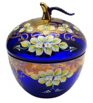 01 potiche em vidro azul cobalto modelado no formato frutiforme, e adornado à mão no estilo Rococó com volutas, arabescos, refinados detalhes geométricos e coloridos motivos florais com pétalas em relevo. Medidas: 20 x 16 cm.