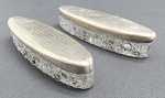 Par de antigos potiches ovais, com tampas em metal espessurado à prata e corpo em cristal incolor lapidado com padrões geométricos em relevo. Medidas: 13 x 3 cm. Tampas com ínfimos pontos amassados.