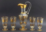 Conjunto composto por 01 jarra no estilo ânfora e 04 taças em cristal incolor; adornadas com faixas, filetes e padrões vegetalistas em dourado. Medidas: 36 x 13 cm; 16 x 8 cm. Douração desvanecida em alguns ínfimos pontos.