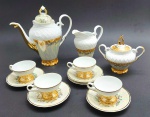 SCHMIDT - Parte de serviço de café composto por 01 bule, 01 leiteira, 01 açucareiro, 04 xícaras de café e 05 pires para xícaras de café; decorados com filetes, motivos florais e vegetalistas em dourado e faixas na cor rosa salmão; em porcelana com acabamento perolizado. Medidas: 23 x 20 cm; 9 x 5 cm.
