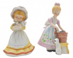 02 bibelôs com a representação de duas meninas em trajes de época e com seus gatinhos; em biscuit policromado. Medidas: 13 x 10 cm; 12 x 7 cm.