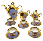 SCHMIDT - Parte de serviço de café com 01 bule, 01 leiteira, 01 açucareiro, 05 xícaras de café e 05 pires para xícaras de café; adornados com douração total e coloridas cenas galantes em suas galerias centrais; pegas das tampas e alças em forma de volutas. Em porcelana. Medidas: 23 x 22 cm; 8,5 x 4,5 cm.