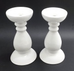 CERÂMICA LUIZ SALVADOR, ITAIPAVA - Par de castiçais com design clássico balaústre e haste torneada; base circular; em cerâmica esmaltada branca, feitos à mão. Medidas: 29 x 14 cm. Pontos com craquelados superficiais; ínfimos fio de cabelo e bicados na base de um dos castiçais; um dos castiçais com ínfimos bicados no topo.