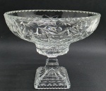 Centro de mesa com borda canelada e amplo bojo decorado com caneluras, motivos geométricos e florais; base quadrangular escalonada tipo pedestal; em cristal translúcido. Medidas: 29 x 24 cm.