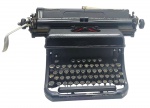 REMINGTON - RAND - MÁQUINA DE ESCREVER - Antiga máquina de escrever da Remington, modelo Rand, fabricada na década de 40. Estrutura robusta em metal com teclas circulares e bordas metálicas. Medida: 23cm. Observação: Não testada. Possui desgastes, marcas, pontos de oxidação e tampas frontal e traseira com nova pintura.
