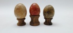 03 diferentes ovos decorativos em rochas lapidadas e polidas; apoiados em bases individuais de madeira torneada. Medidas: 6 x 5 cm; 5 x 4 cm.
