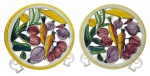 CERÂMICA LUIZ SALVADOR - Par de descansos de mesa adornados com coloridos legumes pintados à mão, filetes em amarelo e detalhes orgânicos vazados; em cerâmica esmaltada. Medidas: 25 x 3 cm. Com ínfimos bicados, fios de cabelo e manchas.