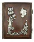 ÁLBUM FOTOGRÁFICO - Antigo álbum fotográfico encadernado em couro, com detalhes vegetalistas e florais em prata, possuindo na parte superior direita um monograma "RF" com adicional de uma espada e datada de 16-12-1901. Bordas das páginas detalhadas em dourado, páginas com espaços para fotos unitárias . Contém 18 páginas. Medida: 33x28cm. Observação: NÃO contém fotos, possui desgastes, marcas de uso e ínfimas avarias.