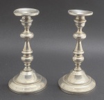 Par de castiçais em prata 900 contrastada, peso total: 809 g; apresentando design clássico com haste torneada com seções arredondadas e anéis decorativos; com outros materiais em seu interior. Medidas: 19,5 cm x 9,5 cm. Amassados em alguns locais no topo e na base.