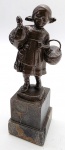Antiga escultura com a representação de uma menina em trajes camponeses de época, segurando uma ave e um cesto; em bronze, apoiada sobre pedestal de mármore quadrangular e escalonado. Medidas: 17 x 5 cm. Mármore com ínfimos bicados.