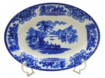 FLOW BLUE - SHANGHAI W. H. GRINDLEY & CO. LTD., ENGLAND - 01 travessa oval de porcelana, em Flow Blue, padrão de decoração Shangai, com ilustração pictórica clássica inspirada em paisagens asiáticas tradicionais, geralmente com construções pagodes, pontes, árvores estilizadas e figuras. "Flow Blue" (ou azul fluido) é um estilo clássico de cerâmica e porcelana antiga do século XIX, famoso por seu padrão azul-cobalto que se "espalha" e borra intencionalmente sobre o fundo branco durante a queima. O padrão "Shanghai" produzido pela manufatura inglesa W. H. Grindley & Co. é um dos designs mais célebres e colecionáveis dentro do estilo flow blue (azul fluido). Introduzido originalmente no final da era vitoriana, por volta de 1891 e produzido até 1914, ele exemplifica a forte influência do estilo Chinoiserie (orientalismo) na Europa da época. Medidas: 36 x 25 cm.