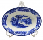 FLOW BLUE - SHANGHAI W. H. GRINDLEY & CO. LTD., ENGLAND - 01 bowl oval de porcelana, em Flow Blue, padrão de decoração Shangai, com ilustração pictórica clássica inspirada em paisagens asiáticas tradicionais, geralmente com construções pagodes, pontes, árvores estilizadas e figuras. "Flow Blue" (ou azul fluido) é um estilo clássico de cerâmica e porcelana antiga do século XIX, famoso por seu padrão azul-cobalto que se "espalha" e borra intencionalmente sobre o fundo branco durante a queima. O padrão "Shanghai" produzido pela manufatura inglesa W. H. Grindley & Co. é um dos designs mais célebres e colecionáveis dentro do estilo flow blue (azul fluido). Introduzido originalmente no final da era vitoriana, por volta de 1891 e produzido até 1914, ele exemplifica a forte influência do estilo Chinoiserie (orientalismo) na Europa da época. Medidas: 28 x 21 cm.