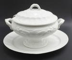 CLEMENTSON BROTHERS (CLEMENTSON BROS.), ROYAL IRONSTONE - Conjunto composto por 01 antiga sopeira em porcelana inglesa, na cor branca, com formato oval e adornada com motivos frutais e vegetalistas em relevo, e 01 travessa oval em porcelana branca (sem marca de manufatura). Royal Ironstone era fabricado pela Clementson Brothers, uma histórica empresa de cerâmica inglesa da era vitoriana, que esteve em atividade entre os anos de 1839 a 1916. Medidas: 36 x 29 cm (sopeira); 45 x 31 cm (travessa). Sopeira com bicado na borda da tampa e fios de cabelo no fundo do bowl.