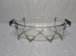 Travessa oval em vidro temperado com suporte em metal prateado. Medindo a travessa 35cm x 23cm x 9cm de altura. Com leve bicado.