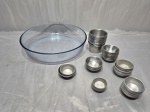 Lote de travessa redonda em vidro temperado e aproximadamente 50 forminhas em alumínio. Medindo a travessa 26cm x 5,5cm de altura. Com leve bicado.