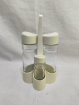 Galheteiro com 5 peças em vidro, tampas e suporte em plástico duro. Medindo a galheta 5cm x 16cm de altura e o suporte 21cm de altura. Com restauro.