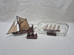 Lote de 3 enfeites na forma de barco em madeira, sendo um dentro da garrafa de vidro. Medindo a garrafa 30cm x 6,5cm x 10cm de altura.