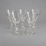 Conjunto composto por seis taças em cristal incolor, destacando-se pelo elegante cálice cônico e pela lapidação geométrica concentrada na parte inferior da copa, prolongada por haste facetada e base circular. Cada taça mede aproximadamente 14  7 cm, reunindo proporções leves e desenho clássico para serviço de vinhos ou licores.
