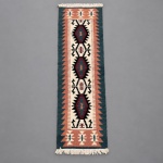 00988 Passadeira tipo kilim, manufatura em lã sobre algodão. Medindo 2,60  0,76 m, composição geométrica de inspiração étnica, apresenta três medalhões centrais alongados, intercalados por motivos estilizados sobre fundo claro. A paleta reúne tons de verde-petróleo, terracota, vinho, preto e creme, com cercadura serrilhada.