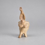 Escultura decorativa em pedra de tonalidade bege rosada, representando elefante em pé com a tromba elevada. Medindo 11 x 8 x 4,5 cm, apresenta execução manual, superfície polida e veios naturais do material, com modelagem simplificada das orelhas, patas e tromba. A postura com a tromba erguida é tradicionalmente associada à boa sorte e prosperidade.