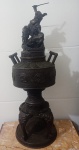 INCENSÁRIO EM BRONZE DE ESTILO ORIENTAL , APRESENTA UM GUERREIRO NO TOPO SOBRE UM DRAGÃO , CORPO DO INCENSARIO DECORADO COM PADRÕES GEOMÉTRICOS CIRCULARES EM RELEVO , PEÇA DECOARTIVA EM BRONZE COM PÁTINA ESCURA . MEDIDAS: 70 CM ALT X 30 CM LARG