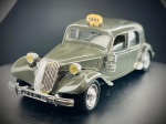 Miniatura Automóvel Clássico  Citroën 15 Six (Táxi), Carroçaria em tom verde cinzento envernizado, com sinalética de táxi amarela no tejadilho, capô dianteiro basculante que revela o bloco do motor detalhado, faróis frontais de tom amarelado clássico, para-choques cromados e chassi inferior metálico. Escala 1:43. Marcas do tempo e de uso.