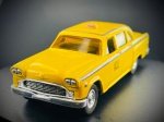Miniatura Automóvel Clássico  1959 Checker Cab (ERTL), Carroçaria em tom amarelo clássico com detalhes axadrezados tradicionais nas laterais e tejadilho, luminoso de teto "TAXI", janelas em tom âmbar, grelha frontal e para-choques cromados destacados, e chassi inferior metálico gravado com as especificações da edição. Med. 03x11x04 cm. Marcas do tempo e de uso.