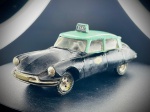 Miniatura Citroën DS 19 Táxi (Metosul), apresentando carroçaria em tom preto, tejadilho e janelas em verde claro, com letreiros "TAXI" nas portas e placar identificativo iluminado no tejadilho. O modelo exibe o chassi em metal/plástico com a gravação de fabrico português. Med. 03x11x03 cm. Marcas do tempo e de uso.