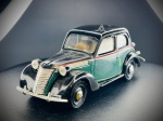 Miniatura Fiat 500 "Topolino" Táxi (Brumm), com carroçaria bicolor em tons de verde e preto, frisos cromados destacados, pneus de borracha e matrícula de época italiana (Milão - MI 180579). O modelo inclui ainda o indicador de táxi montado no tejadilho e pormenores de interior. Escala 1:43. Marcas do tempo e de uso.
