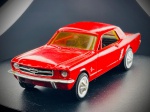 Miniatura Ford Mustang 1964  (Ertl), com carroçaria em tom vermelho vivo, grelha frontal e para-choques cromados em relevo, vidros em tom âmbar e elegantes pneus de faixa branca com tampas de cubo detalhadas. O chassi em relevo exibe toda a identificação oficial da marca Ertl, o número de série de produção (2400G) e a especificação do modelo histórico. Escala 1:43. Marcas do tempo e de uso.