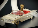 Miniatura Chevrolet Impala Convertible com Figura (Vitesse), com carroçaria em tom creme/marfim, grelha frontal e para-choques cromados em relevo, interior detalhado em vermelho vibrante, pneus com faixa branca e a inclusão original de uma figura de autoridade/oficial perfilada no habitáculo com os braços erguidos. O chassi em relevo exibe toda a identificação oficial da marca Vitesse, a indicação de fabrico português. Med. 03x12x04 cm. Marcas do tempo e de uso.