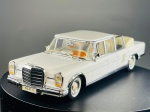 Miniatura Mercedes-Benz 600 Landaulet "SCV 1" - Vitesse, (Versão Papal / Estado "SCV 1"), com carroçaria em tom branco clássico, grelha frontal cromada imponente, matrículas oficiais "SCV 1", interior detalhado em tons claros com painel acobreado, capota traseira recolhida simulada em bege, pneus com faixa branca e inclusão de figura miniatura de passageiro com chapéu vermelho. O chassi inferior exibe as gravações oficiais da marca Vitesse. Escala 1:43. Marcas do tempo e de uso.