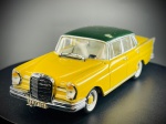 Miniatura Mercedes-Benz 220 SE (W111)  Vitesse,  apresentando carroçaria em tom amarelo vivo com tejadilho em verde escuro, grelha frontal cromada com emblema, matrículas detalhadas ("F-JM 126"), autocolante de nacionalidade alemã ("D") na retaguarda e pneus de faixa branca. A base inferior exibe com clareza as marcas de fabrico da Vitesse, a escala 1:43 e a referência ao modelo Mercedes-Benz 220. Escala 1:43. Marcas do tempo e de uso.