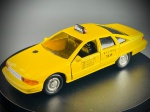 Miniatura Chevrolet Caprice Taxi de Nova Iorque (1993)  Road Champs, com acabamento em amarelo vivo caraterístico dos táxis nova-iorquinos, tejadilho com luminoso de teto ("OFF DUTY" / 7N39), inscrições detalhadas nas portas com tarifas e identificação da frota ("N.Y.C. TAXI 7N39"), e portas dianteiras bem como a bagageira com aberturas funcionais. A base inferior exibe claramente as marcas de fabrico da Road Champs e o ano de 1993. Med. 03x12x04 cm. Marcas do tempo e de uso.