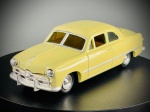 Miniatura 1949 Ford Coupe  Ertl, escala 1:43, carroçaria em tom amarelo claro, janelas com tonalidade âmbar/fumada, grelha frontal e para-choques detalhados com acabamento metalizado prateado, frisos laterais e jantes cromadas. A base inferior exibe em relevo a marca Ertl. Marcas do tempo e de uso.