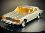 Miniatura Rolls-Royce  Berlina de Luxo, carroçaria em tom prateado, vidros e para-brisas em tom âmbar/amarelado, interior detalhado em tons contrastantes e jantes cromadas de acabamento brilhante. O modelo conta com partes móveis, permitindo a abertura do capô dianteiro e das portas laterais. Med. 03x13x04 cm. Marcas do tempo e de uso.