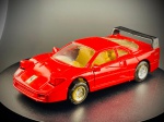 Miniatura Ferrari F40, icônico superdesportivo em tom vermelho vivo (Rosso Corsa), caracterizado pelo imponente aileron traseiro em preto, tampa do motor em acrílico transparente com ranhuras de ventilação, faróis escamoteáveis dianteiros e emblema do Cavallino Rampante aplicado no capot. Med. 03x11x04 cm. Marcas do tempo e de uso.