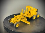 Miniatura de Motoniveladora / Máquina de Terraplanagem, Motoniveladora (ou niveladora de estrada) em tom amarelo industrial, equipada com lâmina central de nivelamento ajustável, eixo dianteiro direcional, cabine fechada para o operador e conjunto de rodas traseiras duplas com pneus sulcados em borracha. "SUPERMIN", a referência "ARPRA" "MADE IN BRAZIL", complementada com inscrições e logótipos decorativos da marca "KOMATSU". Med. 04x10x05 cm. Marcas do tempo e de uso.