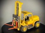 Miniatura de Empilhador Industrial / Empilhadeira, escala 1:43, Empilhador industrial de grande porte em tom amarelo e preto, com torre de elevação vertical extensível, garfos frontais ajustáveis em vermelho, tejadilho de proteção do operador perfurado, assento detalhado e pneus sulcados em borracha (rodado duplo no eixo dianteiro motriz).  "MADE IN BRAZIL", complementada com inscrições e logótipos decorativos da marca "KOMATSU".Marcas do tempo e de uso.