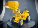 Miniatura de Pá Carregadora / Máquina de Terraplanagem, escala 1:50. Pá carregadora industrial na cor amarela clássica, com posto de condução aberto equipado com volante e assento pretos, escape vertical metalizado, grelha frontal com inscrição da marca e braços de elevação articulados com balde frontal de grande capacidade.  "SUPERMIN", a referência "ARPRA", a escala "1:50" e a origem "MADE IN BRAZIL", além de inscrições laterais identificativas do modelo "140B" e emblemas "CAT". Marcas do tempo e de uso.