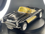 Miniatura de Automóvel Desportivo Chevrolet Corvette (1957), Automóvel desportivo clássico conversível em tom preto com detalhes laterais contrastantes em creme, equipado com para-brisas panorâmico em tom âmbar, portas e capô dianteiro móveis/articulados.com acabamentos cromados na grelha frontal, para-choques e jantes raiadas de design desportivo, apresentando placa de matrícula frontal e traseira com a inscrição "MA-1957". Marcas do tempo e de uso.