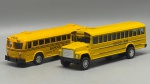 Miniaturas em Metal e Plástico  Autocarros Escolares Norte-Americanos ("School Bus"), duas miniaturas de autocarros escolares norte-americanos (School Bus), fiéis representações dos icónicos veículos de transporte de estudantes. As peças destacam-se pela tonalidade amarela brilhante com faixas pretas decorativas, inscrições regulamentares de segurança ("School Bus", "Emergency Exit" e braço sinalizador "STOP") e chassis detalhados em plástico resistente. Med. 06x12x04 c e 05x11x04 cm. Marcas do tempo e de uso.