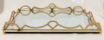 Bandeja com fundo em espelho de cristal bisotado, bordas altas como guirlandas, em metal dourado em feitio de bolinhas, quatro pés bola. Med. 42x24x5 cm.