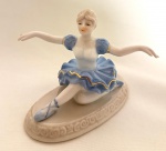 Escultura de coleção representando bailarina, em porcelana vitrificada, ao gosto Lladró, em perfeito estado. Med. 11x9x12 cm.