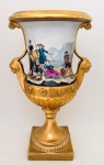 Vaso ornamental todo em porcelana europeia, em formato de ânfora, corpo decorado com cena campestre alças decoradas com mascarões femininos em relevo, detalhes a ouro, motivos florais e inspiração neoclássica, com base quadrangular. Med. 35x23 cm.