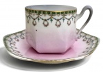 FRANÇA LIMOGES -Elegante xícara para chá com pires em fina porcelana Limoges U.C. France, em formato facetado, decoração em delicados festões florais com detalhes dourados e fundo em degradê rosa. Peça de refinado acabamento, ideal para colecionadores de porcelanas francesas e composições de mesa clássicas. Acompanha seu respectivo pires.